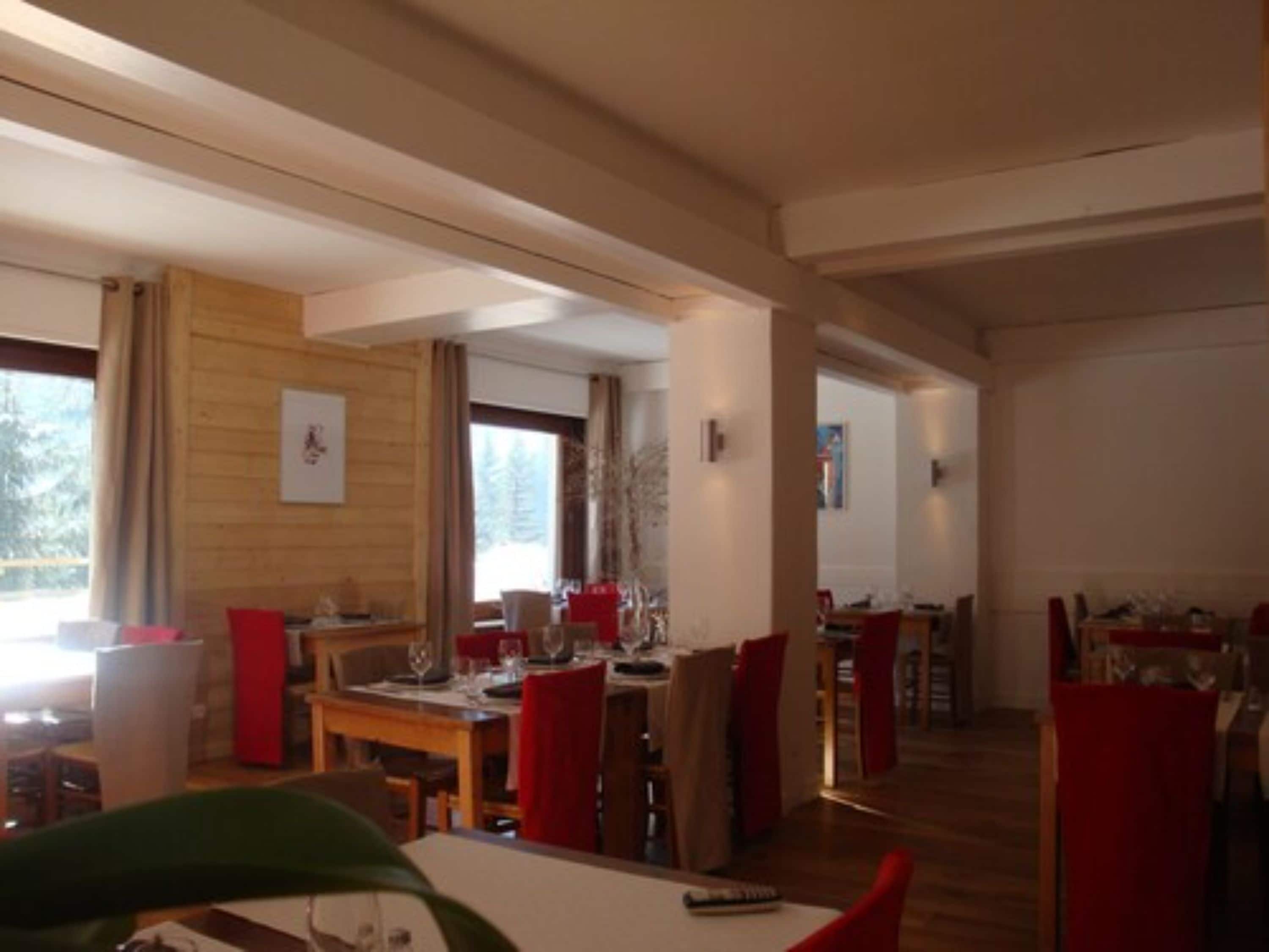 Un comedor amplio con paredes de madera y ventanas grandes, que cuenta con varias mesas y sillas.