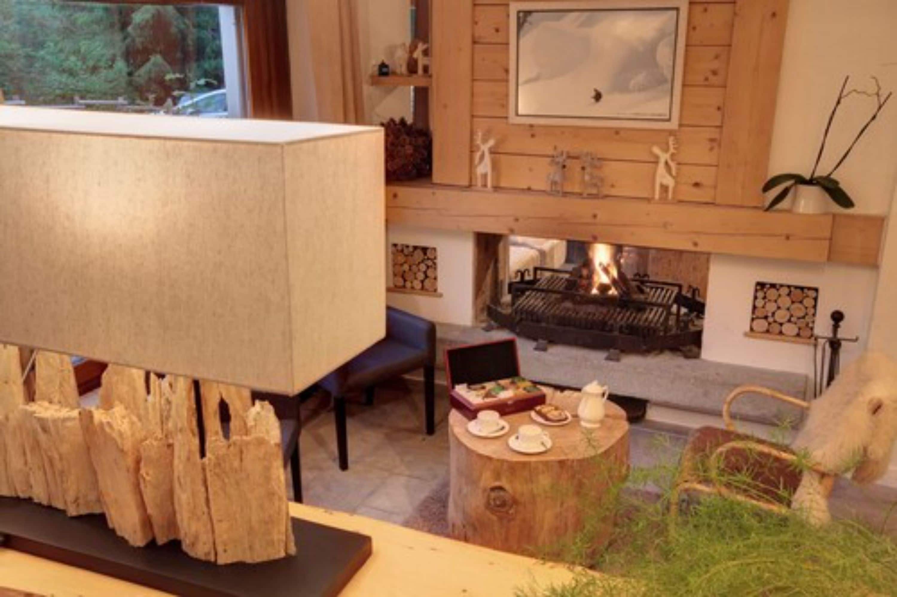 Ein gemütliches Wohnzimmer mit Kamin, Holzvertäfelung und einem Essbereich mit Tee-Gedeck.