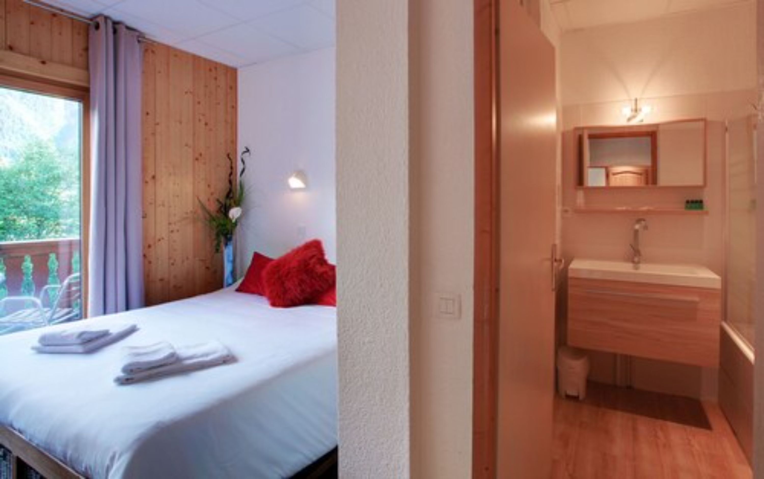 Un dormitorio con cama, almohada roja y ventana con cortinas.