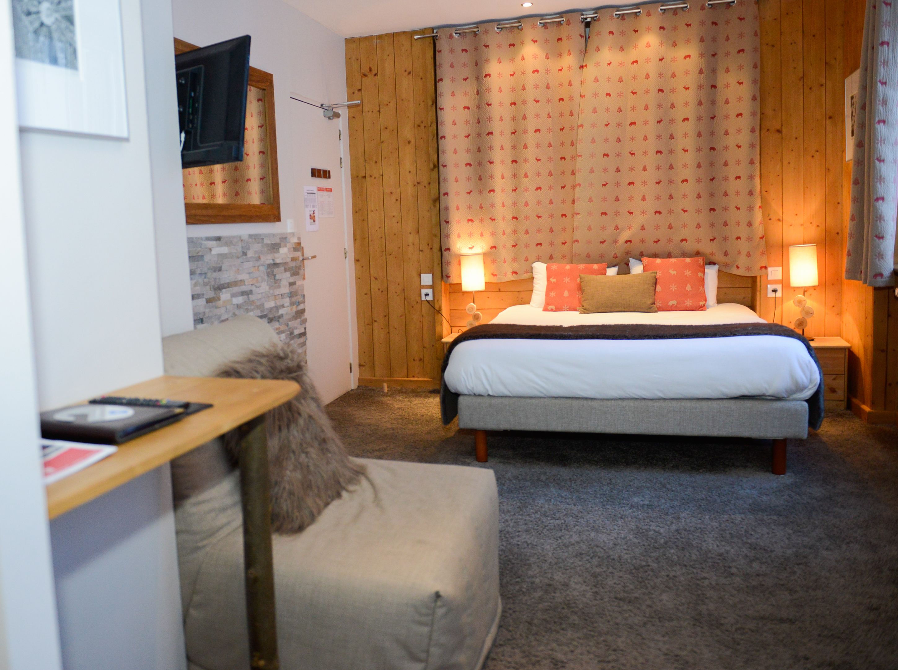 A cozy bedroom with a large bed, two bedside tables, a wooden headboard, and a small desk with a chair.