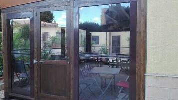 Un espace extérieur abrité, doté d’une structure en bois et de portes en verre.