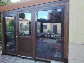 A covered outdoor seating area with a wooden structure and glass doors. - Hotel d'Orleans (Palermo)