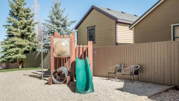 Explore the backyard play area with a slide and climbing structure, surrounded by trees and a wooden fence.