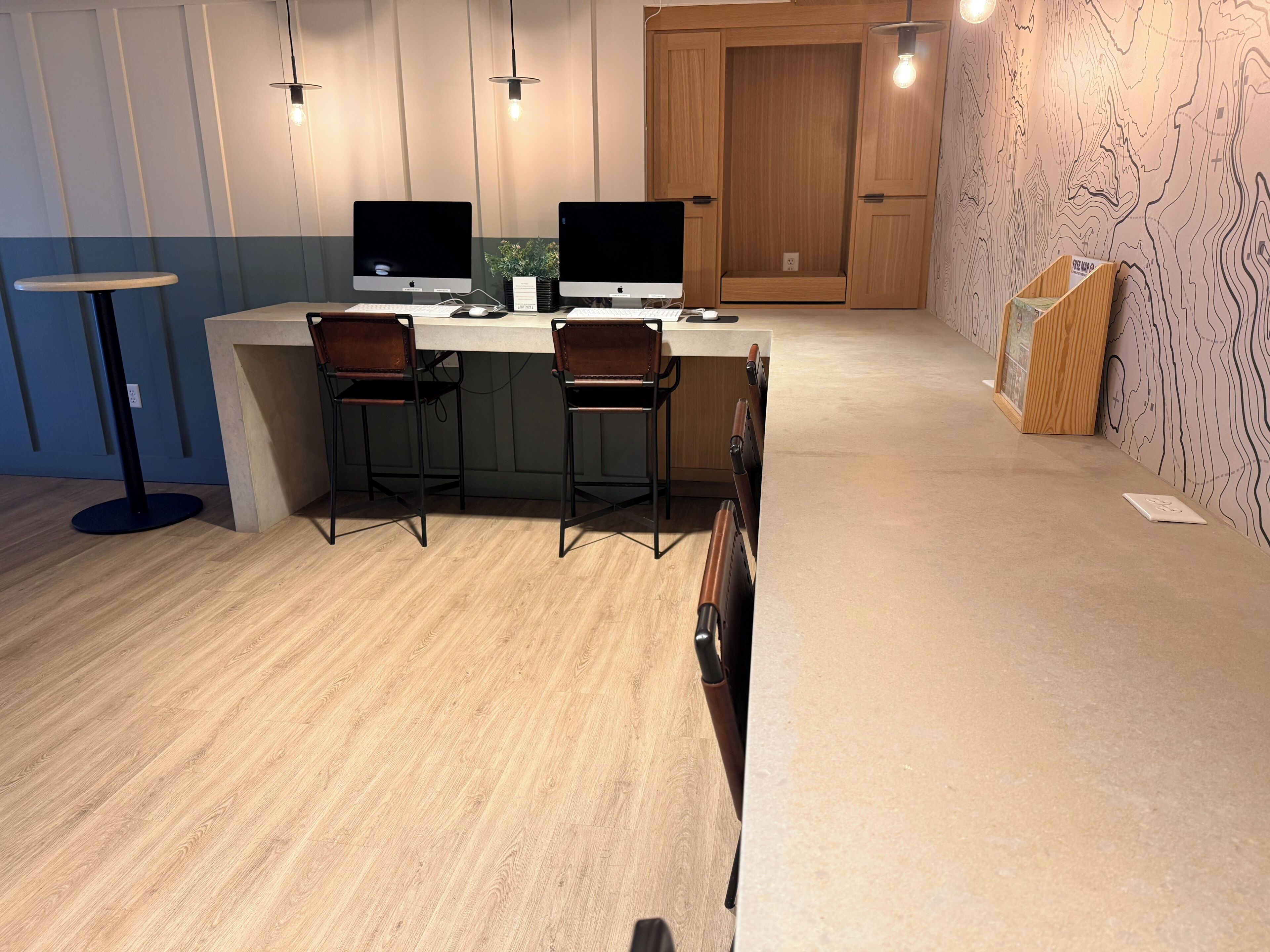 A modern kitchen with two Apple iMacs, a bar area with stools, and a wooden cabinet.