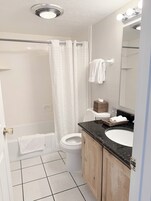 Ein Badezimmer mit Dusche, Toilette, Waschbecken und Spiegel.