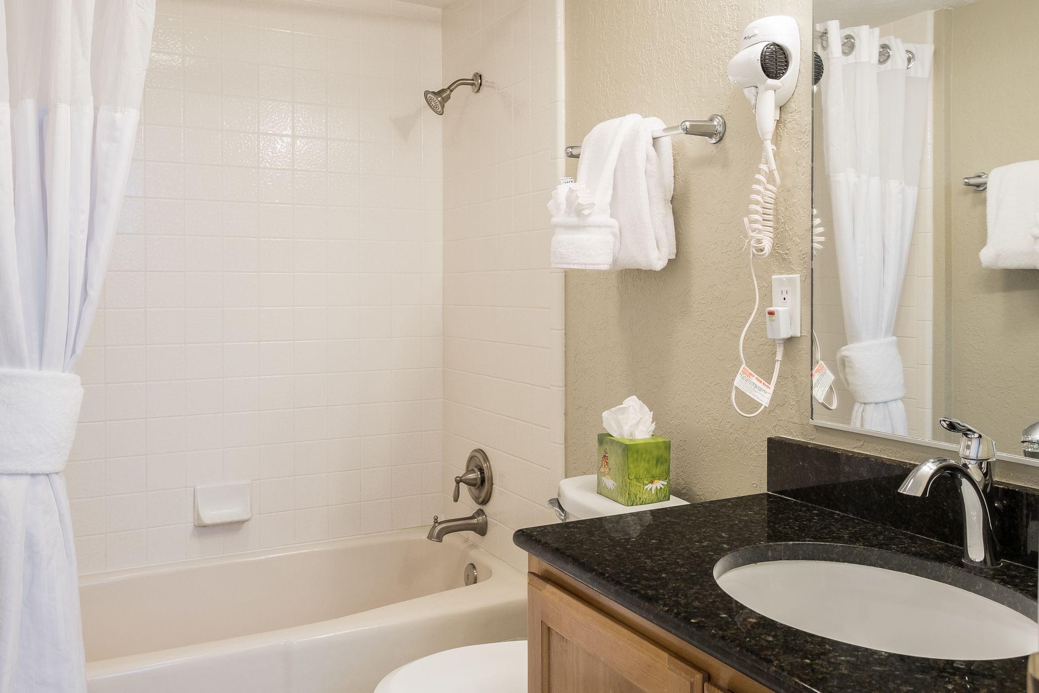 A bathroom with a bathtub, a sink, a hairdryer, and a towel rack.