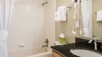 A bathroom with a bathtub, a sink, a hairdryer, and a towel rack.
