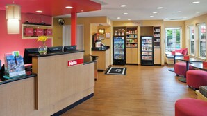 Eine Hotelhalle mit Rezeption, Sitzgelegenheiten, Verkaufsautomaten und einer mit Getränken gefüllten Kühltheke.