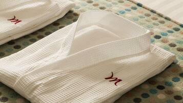 Neatly folded white towels with a red logo on a bed with a polka dot patterned bedspread.