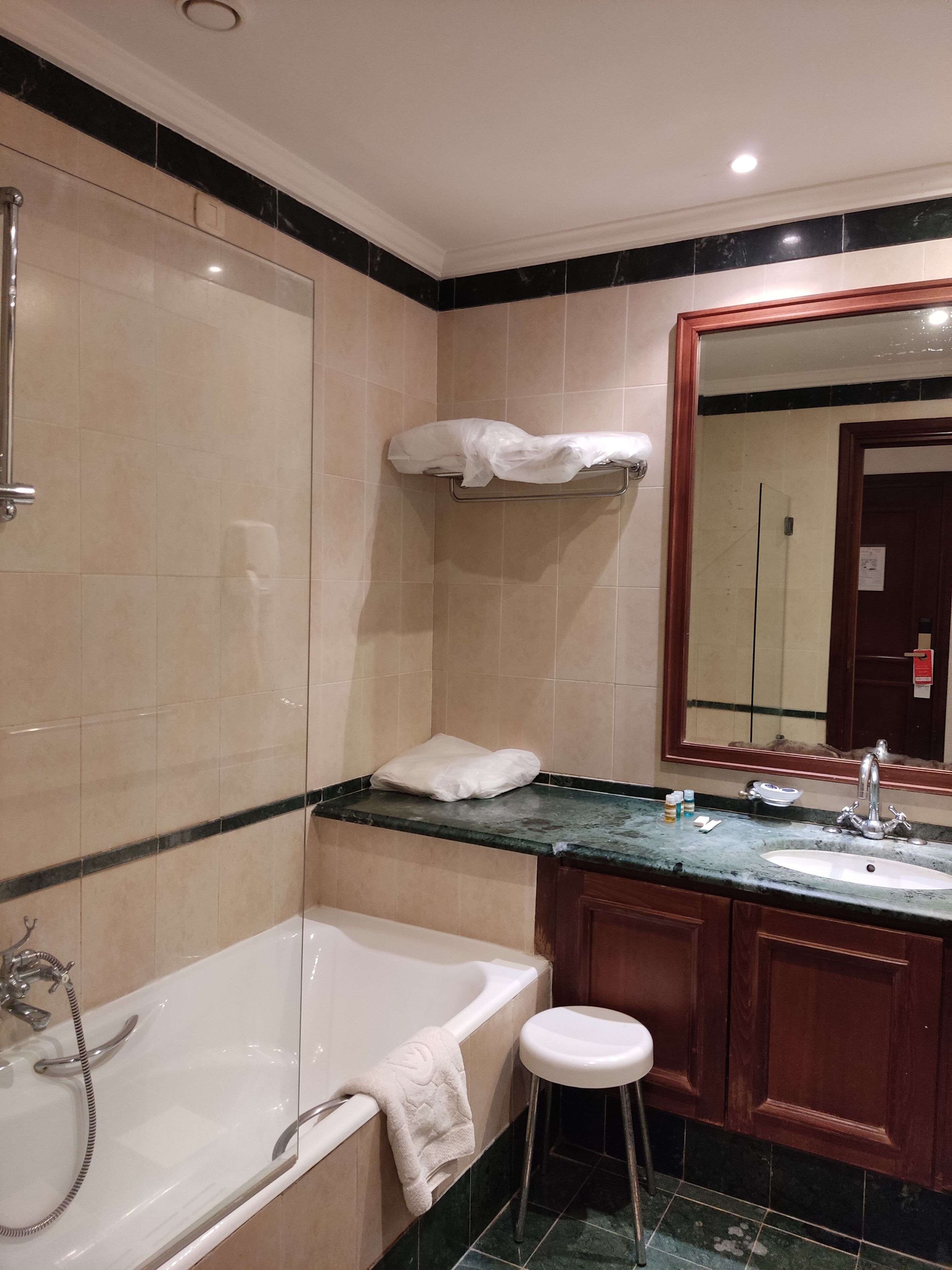 A bathroom with a bathtub, a sink, a mirror, and a towel rack.