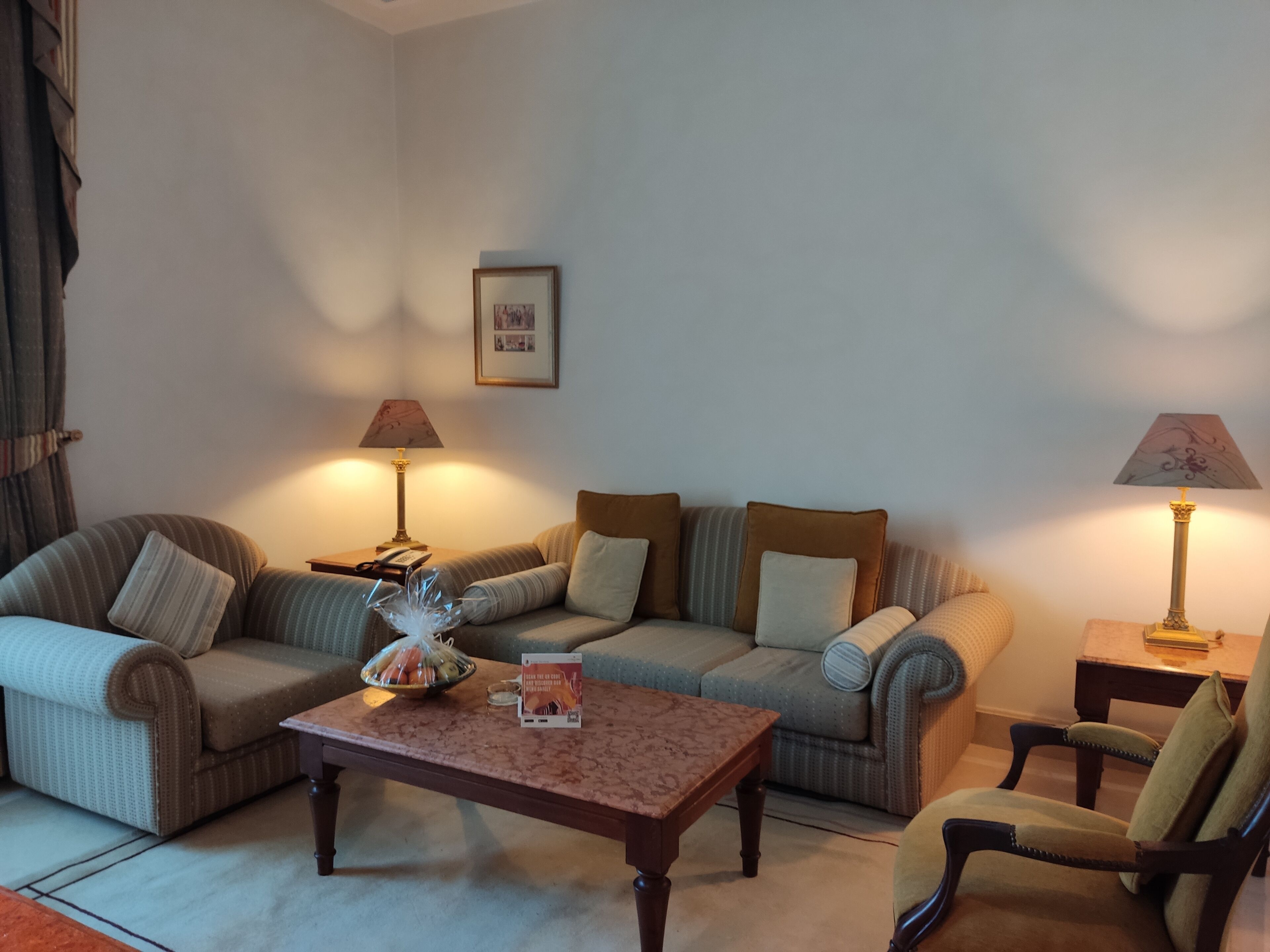 Una sala de estar con un sofá, sillones, una mesa de centro y dos lámparas.