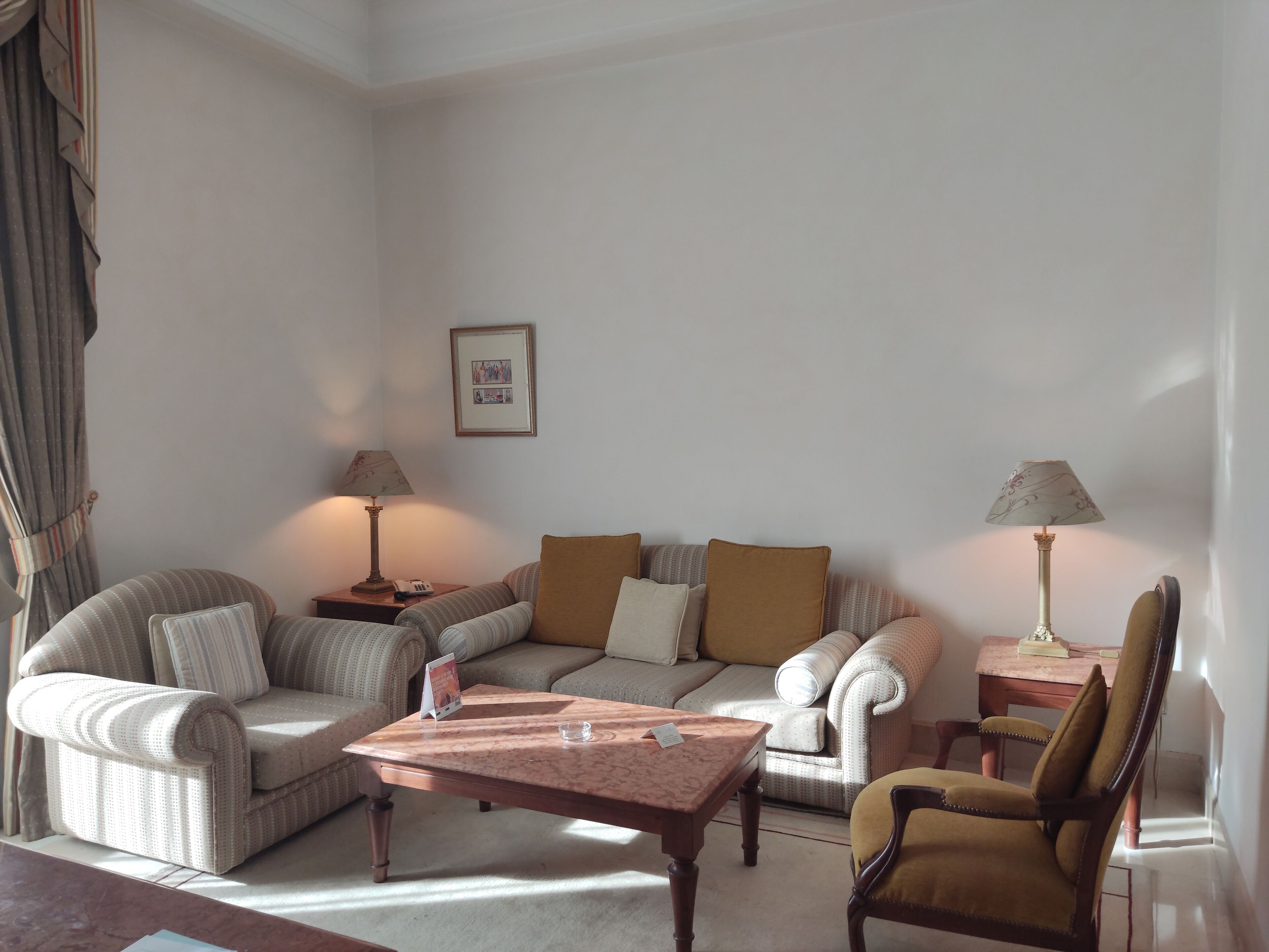 Un salon avec un canapé, des fauteuils, une table basse et des lampes.