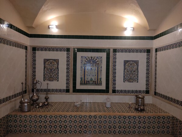 Un baño con elaborados trabajos en mosaico, una bañera y un lavamanos adornado con objetos decorativos.