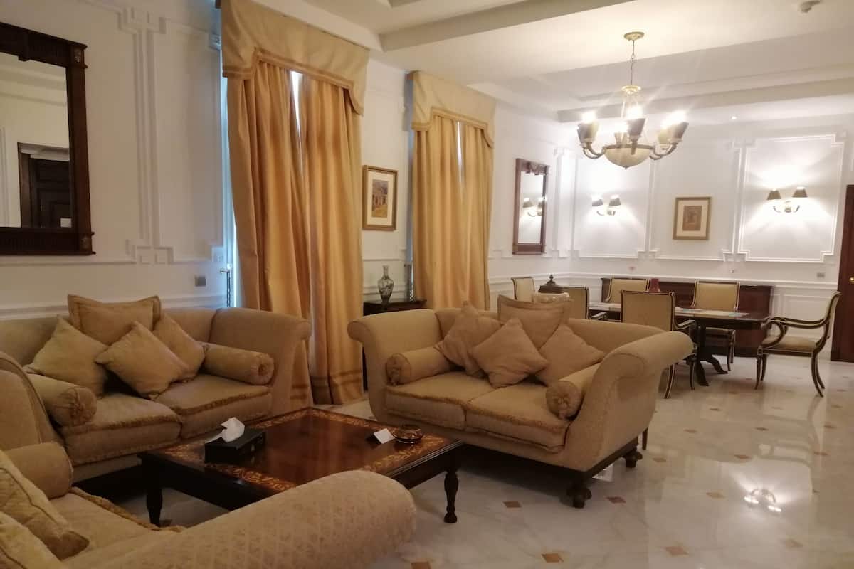 Uma sala de estar ampla com dois sofás bege, uma mesa de centro e um espaço de jantar com um candelabro.