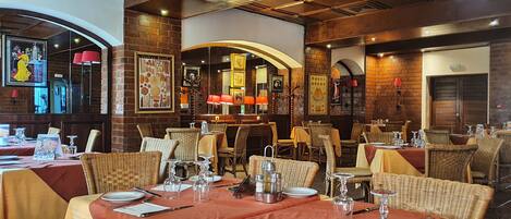 Un restaurante con paredes de ladrillo, sillas de mimbre y manteles rojos.