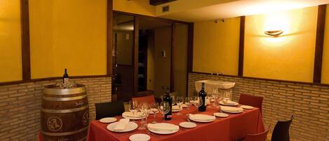 Un coin repas avec une table dressée pour quatre personnes, un tonneau à vin et un mur en briques.