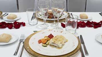 A dining table set with plates of food, wine glasses, and cutlery.