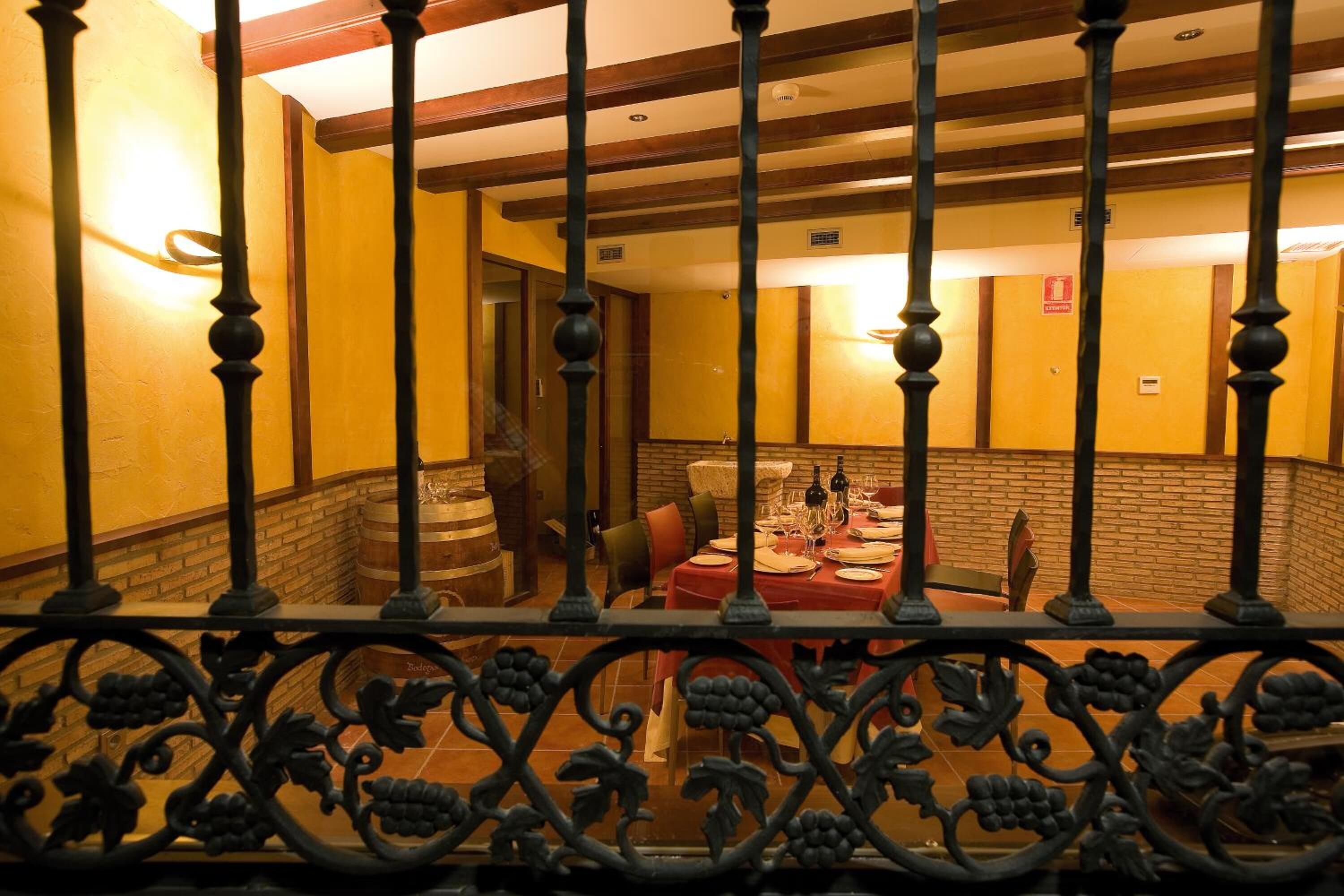Zona de menjador amb paret de maó, bigues de fusta i taula preparada per a una posta.