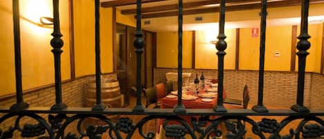 A dining area with a brick wall, wooden beams, and a table set for a meal.