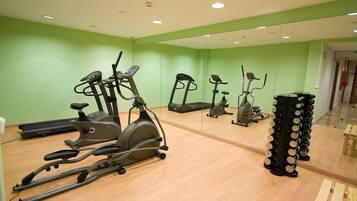 Une salle de sport équipée de divers appareils d’exercice, notamment des tapis de course, des vélos d’appartement et un appareil de marche en escalier.