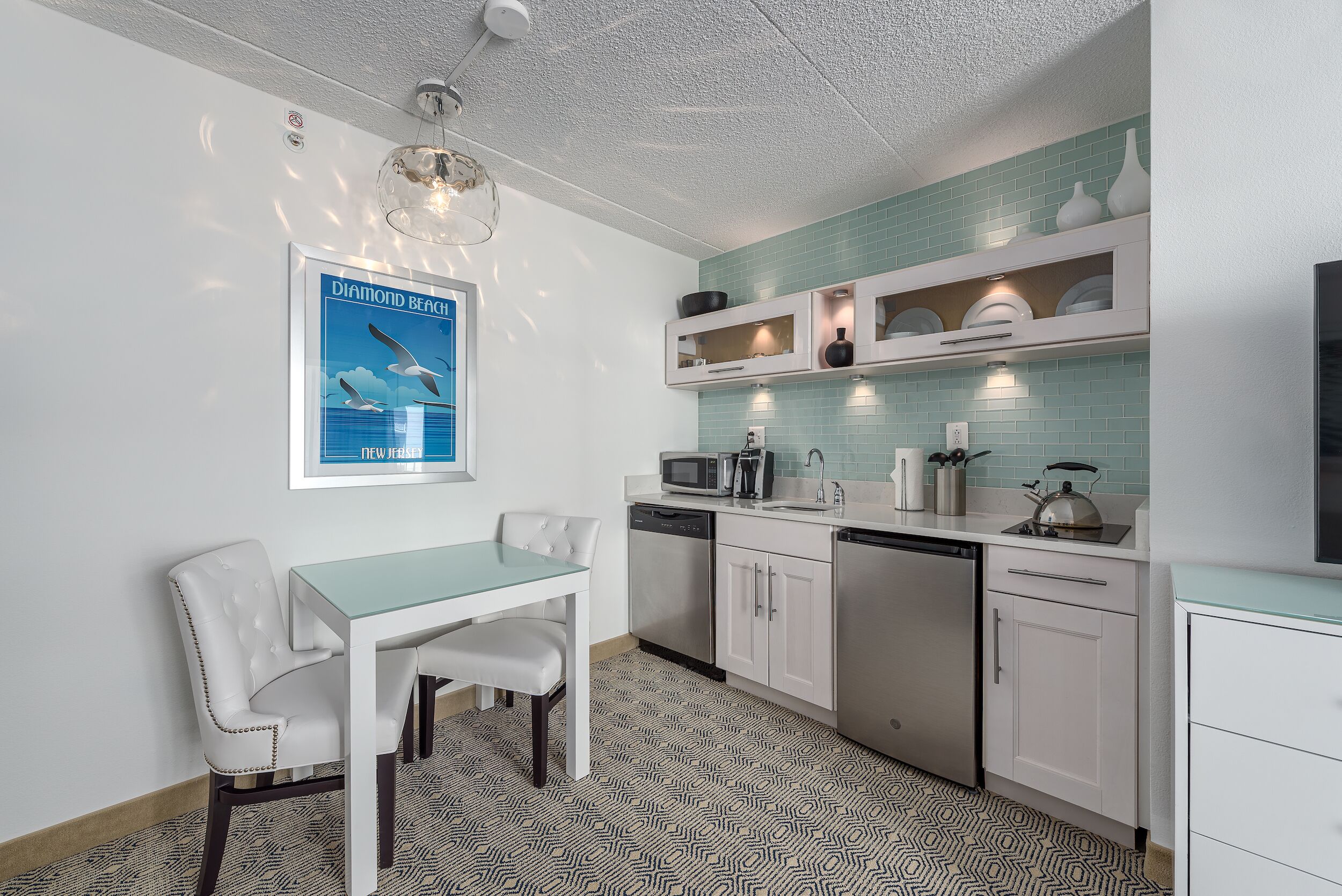 A modern kitchen with white cabinetry, a dining area with a white table and chairs, and a tiled backsplash.
