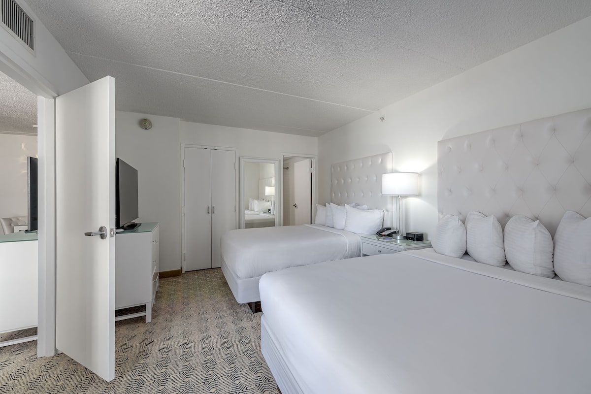 A hotel room with two beds, a TV, a bedside table, and a wardrobe.
