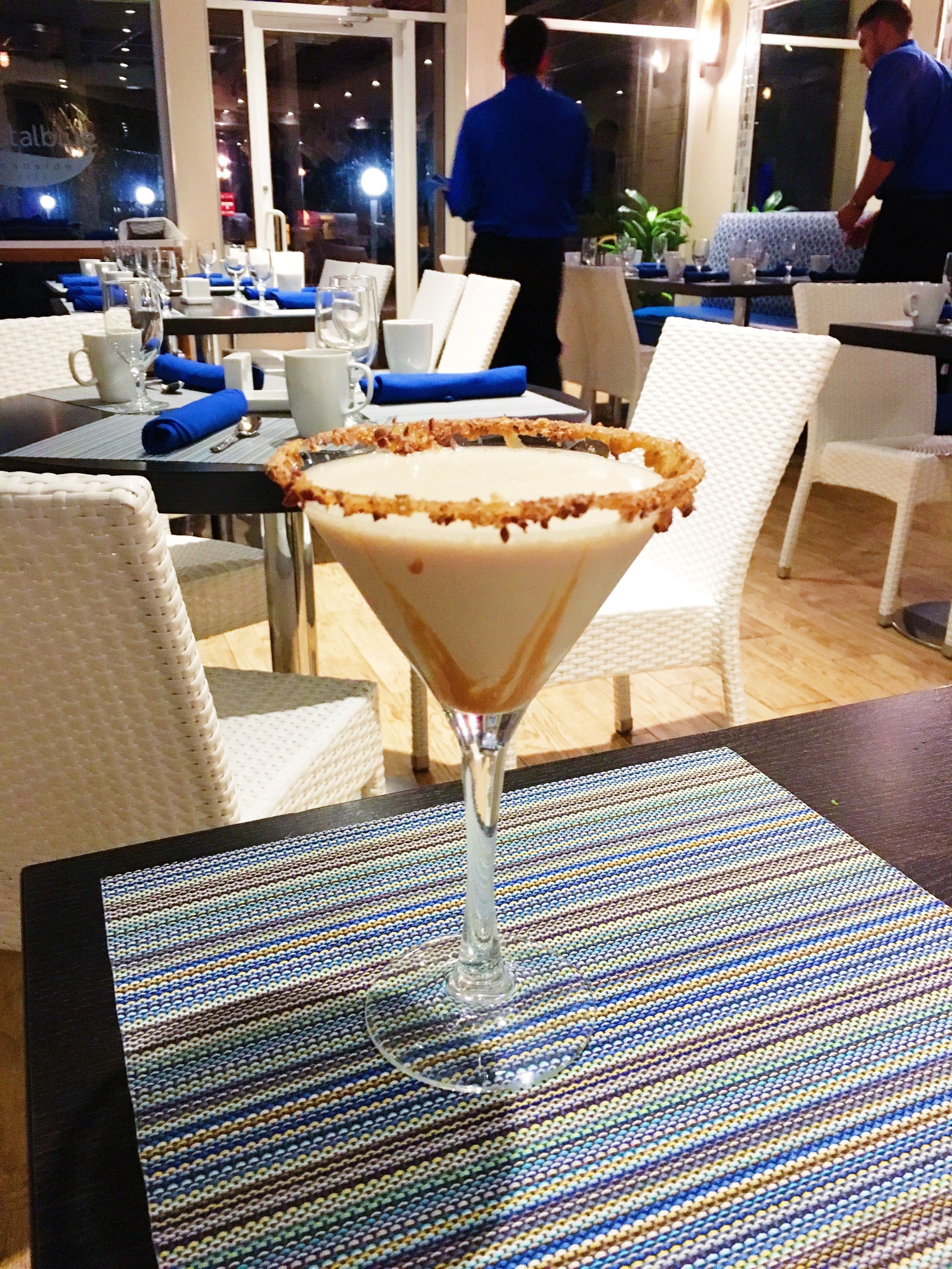 A dining area with tables set for two, featuring a martini glass with a dessert garnish.