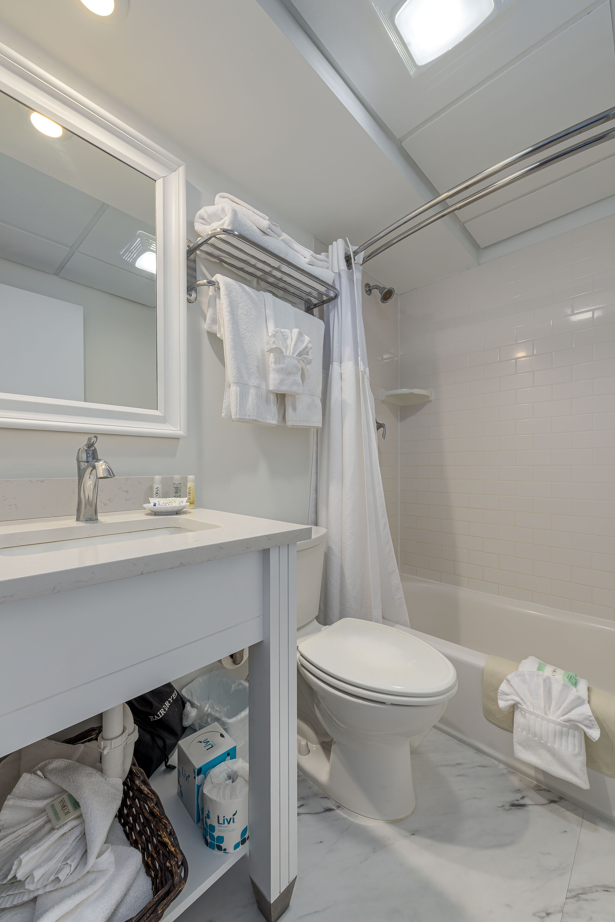 A modern bathroom with a white sink, a toilet, a shower area, and a mirror.