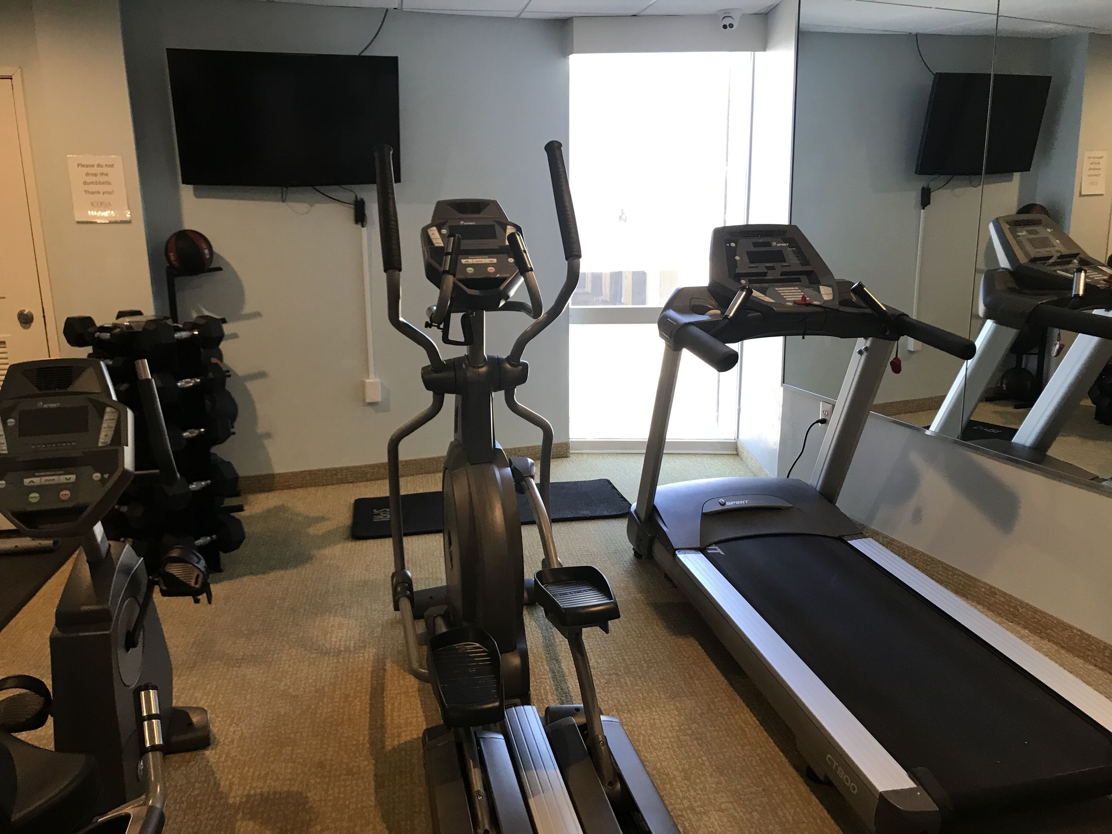 A gym with cardio equipment including a treadmill, elliptical, and stationary bikes.