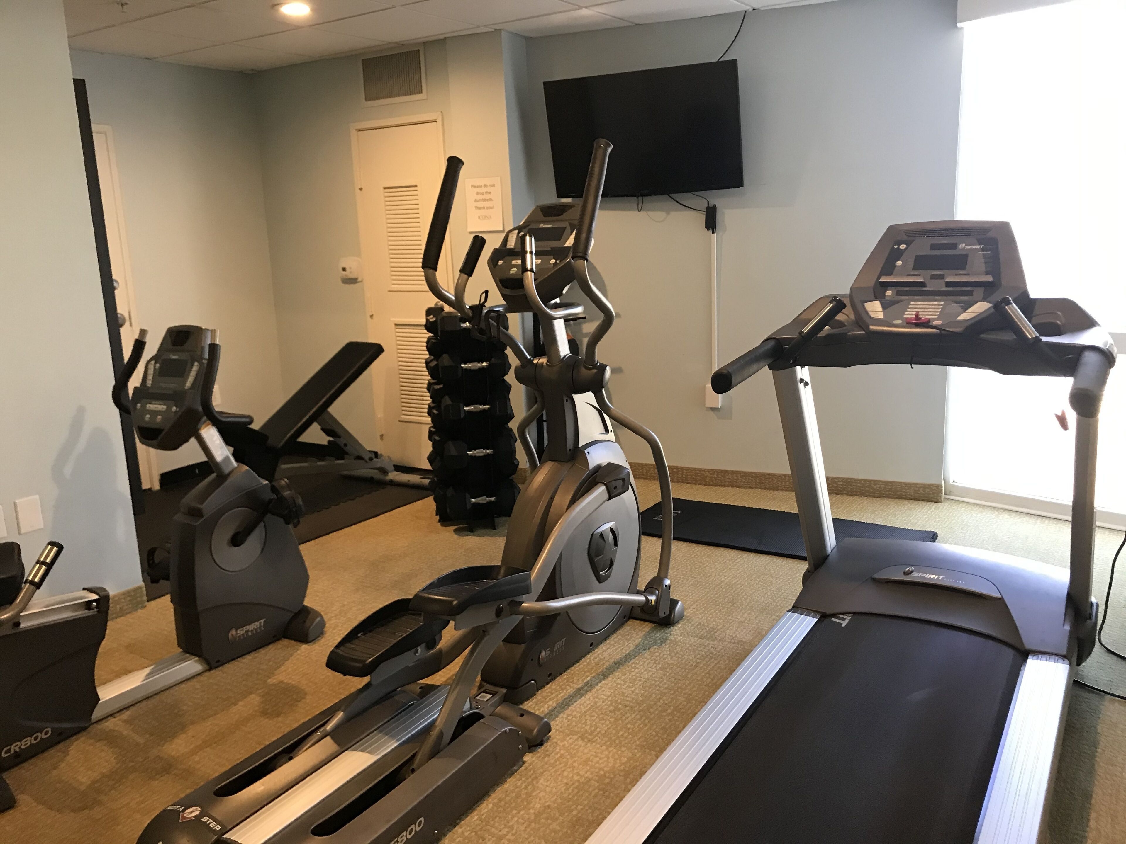A home gym with a treadmill, elliptical, and stationary bike.