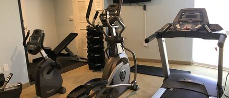 A home gym with a treadmill, elliptical, and stationary bike.