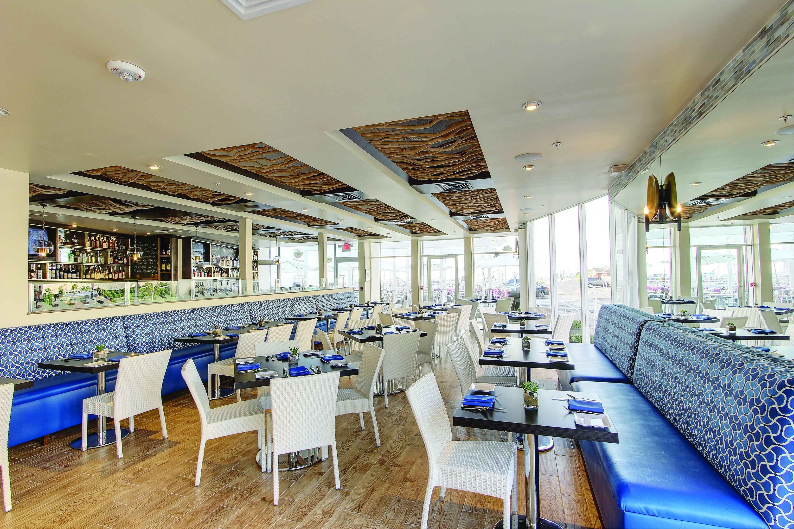 A restaurant with a bar area, booths, and high ceilings with patterned designs.