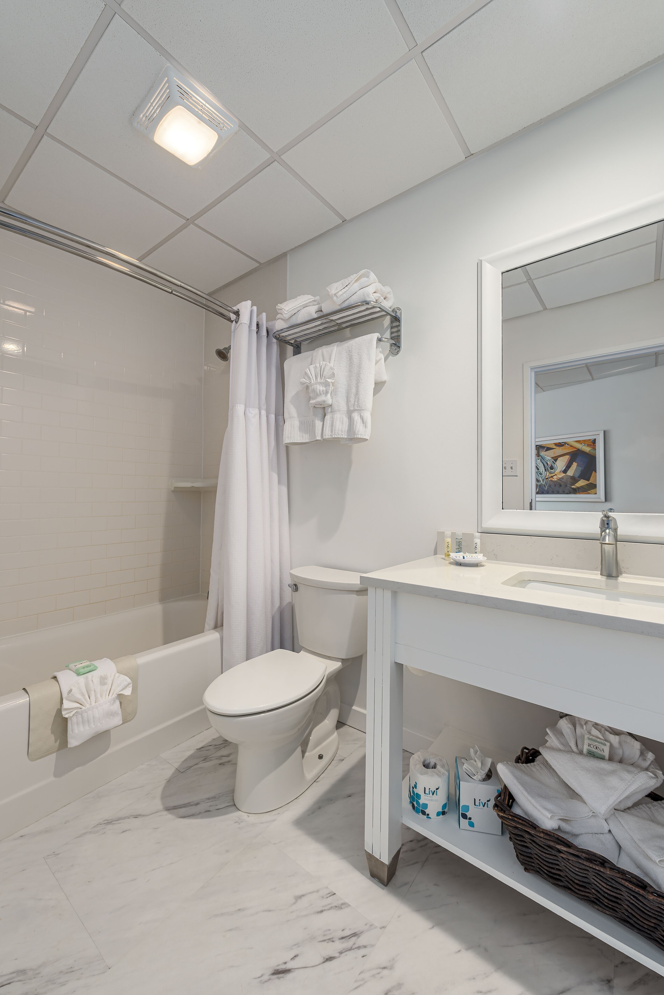 Un baño moderno con bañera, inodoro y lavamanos. Hay toallas y artículos de aseo en la encimera.