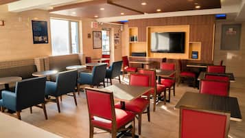 A restaurant with booths and tables, a flat-screen TV mounted on the wall, and a fire hose sign on the wall.