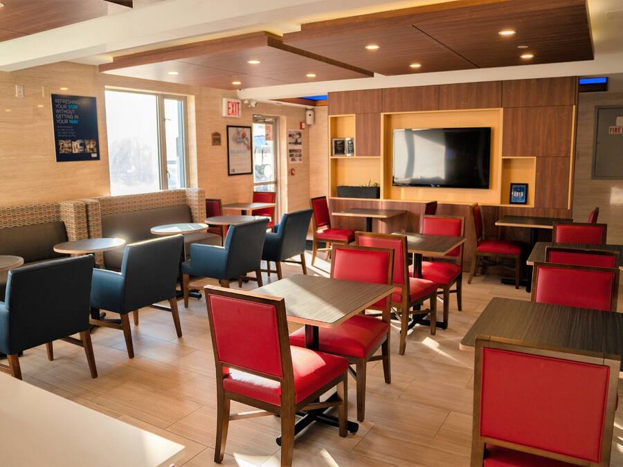 A restaurant with booths and tables, a flat-screen TV mounted on the wall, and a fire hose sign on the wall.