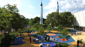 Un parque con áreas de juegos, árboles y dos estructuras altas que parecen cohetes.