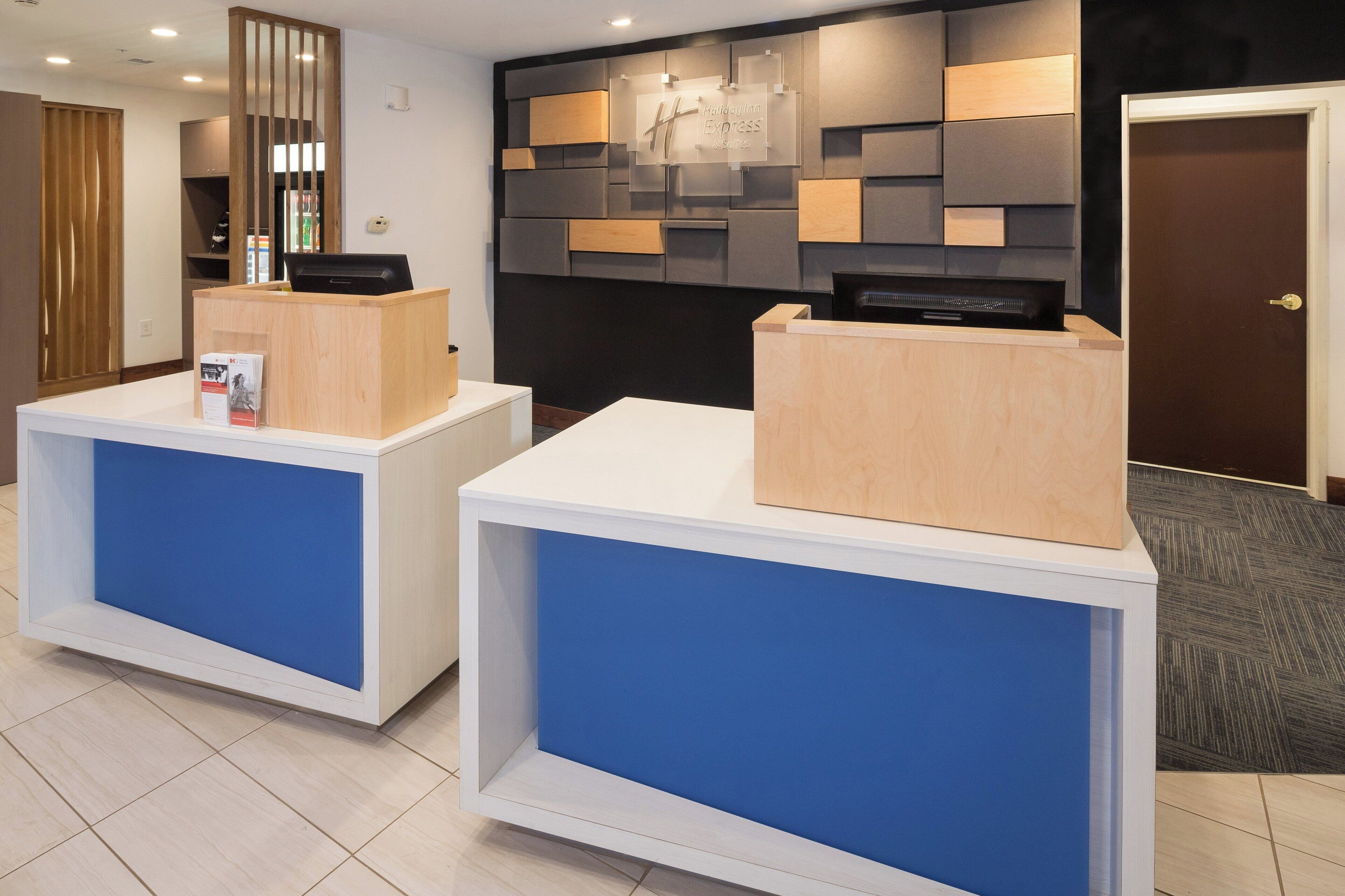 A reception desk with a wooden finish and a blue panel, a wall-mounted sign, and a door with a key in the lock.