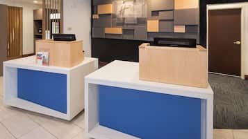 Un mostrador de recepción con acabado de madera y un panel azul, un letrero en la pared y una puerta con llave en la cerradura.