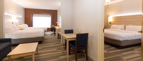 Ein Hotelzimmer mit zwei Betten, einem Schreibtisch, einem Stuhl und einem Sofa.