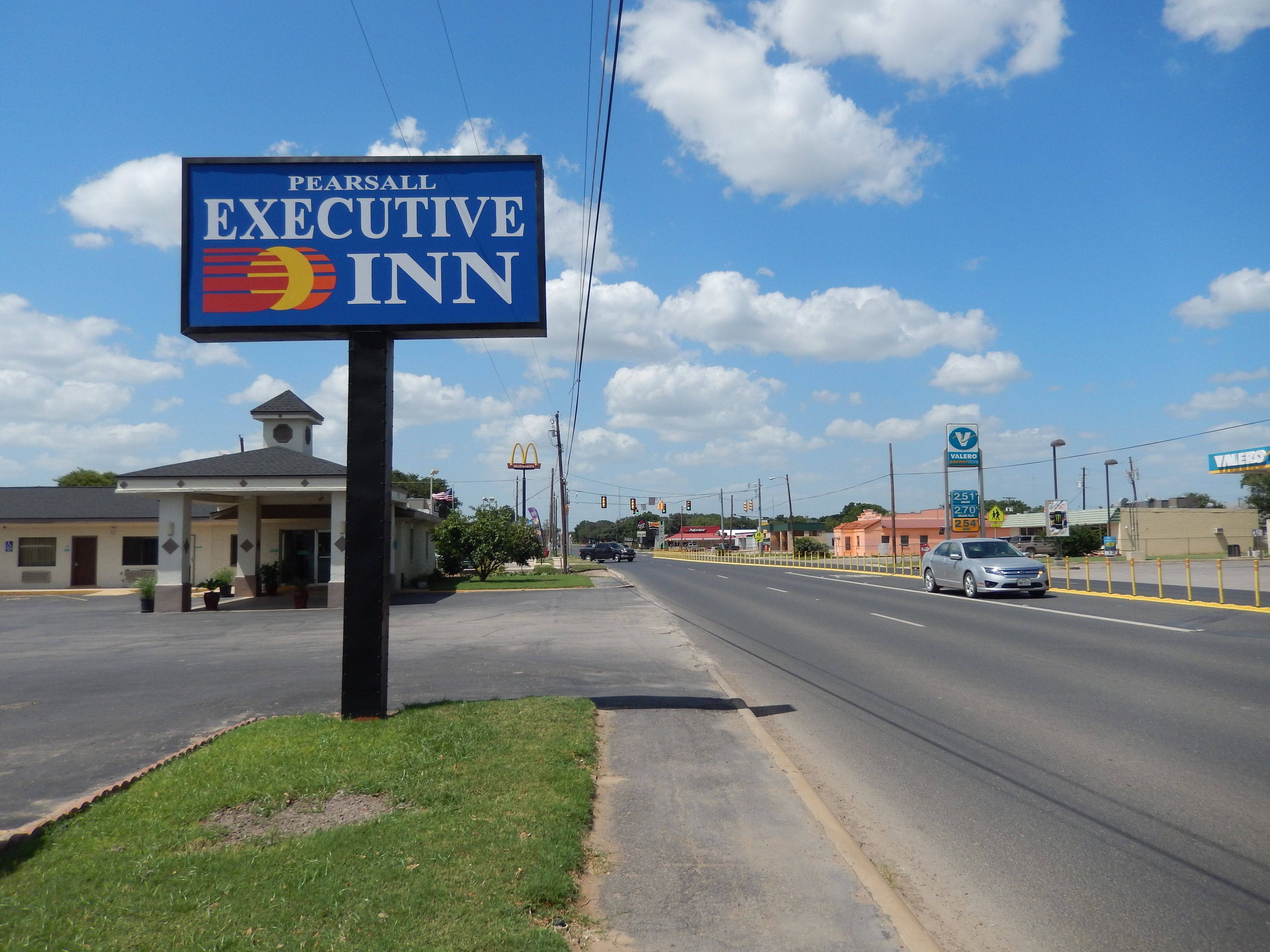 A sign for Pearsall Executive Inn with a clear view of the road and surrounding buildings.