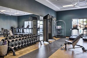 Une salle de sport équipée de tapis de course, d’appareils de musculation et d’un porte-haltères.
