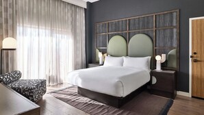 A modern hotel room with a large bed, a desk, and a chair.