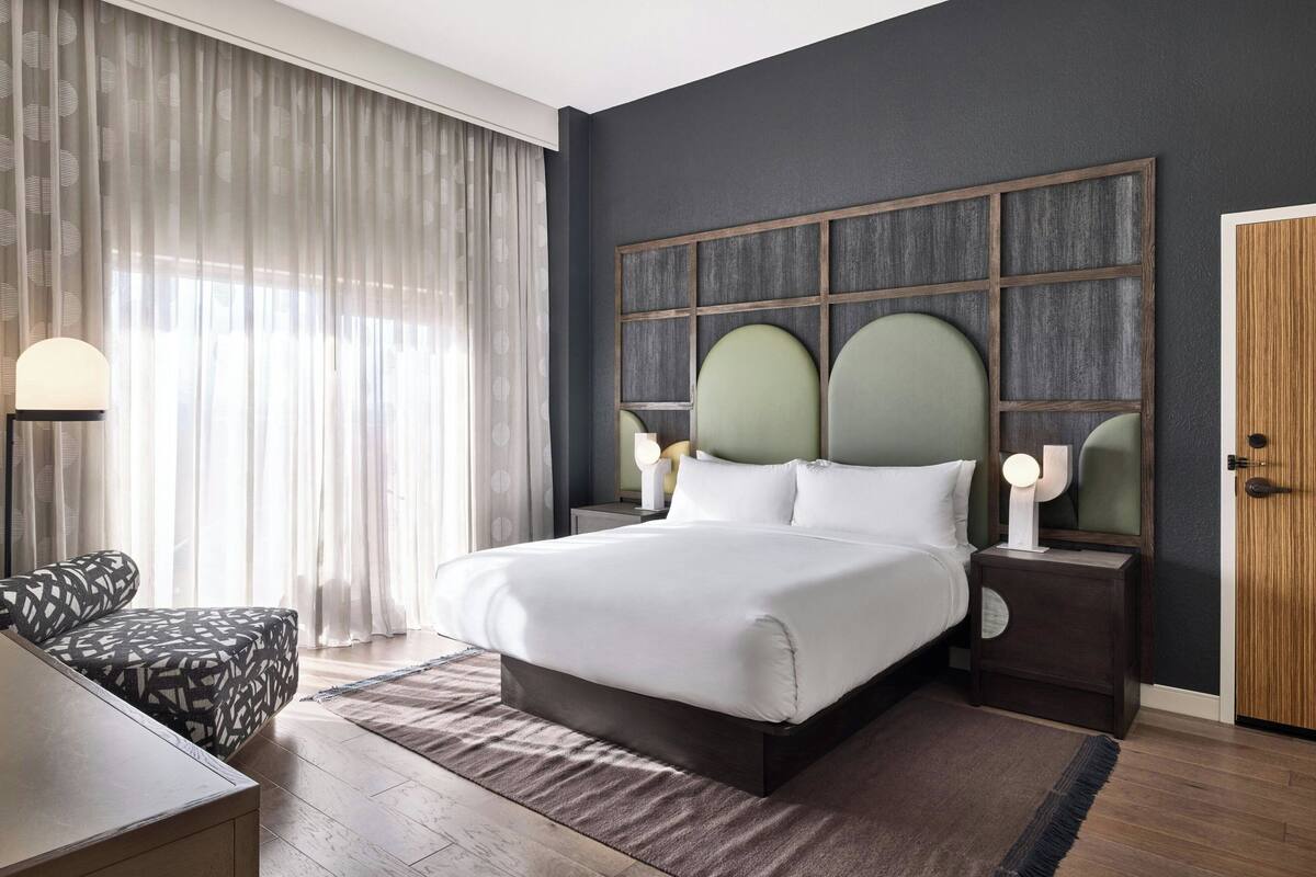 Ein modernes Hotelzimmer mit einem großen Bett, einem Schreibtisch und einem Sessel.