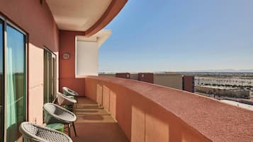 A balcony with wicker chairs, a glass door, and a view of a cityscape.
