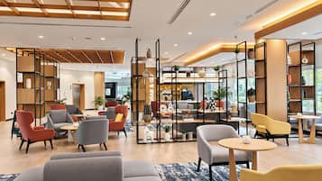 Eine moderne Hotelhalle mit Sitzbereichen, einer Rezeption und einer Kaffeebar.
