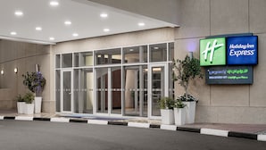 A Holiday Inn Express building with a glass entrance, potted plants, and signage in multiple languages. - Holiday Inn Express Dubai, Internet City by IHG (Dubai)