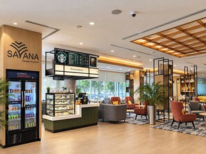 A modern interior with a Starbucks Express Essentials kiosk, seating area with chairs, and a large window offering a view of the outdoors. - Holiday Inn Express Dubai, Internet City by IHG (Dubai)