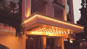 A building with a covered entrance area, palm trees, and a series of lights. - T24 Retro (Mumbai)