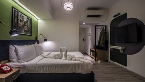 A modern hotel room with a large bed, a bedside telephone, a flat-screen TV mounted on the wall, and a framed picture above the bed. - T24 Retro (Mumbai)