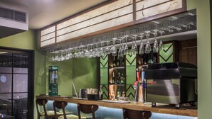 A bar area with a counter, stools, hanging glasses, and a coffee machine. - T24 Retro (Mumbai)